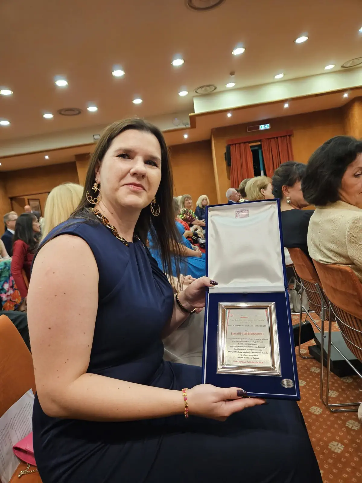 Účastníčka slávnostného večera s otvorenou plaketou
